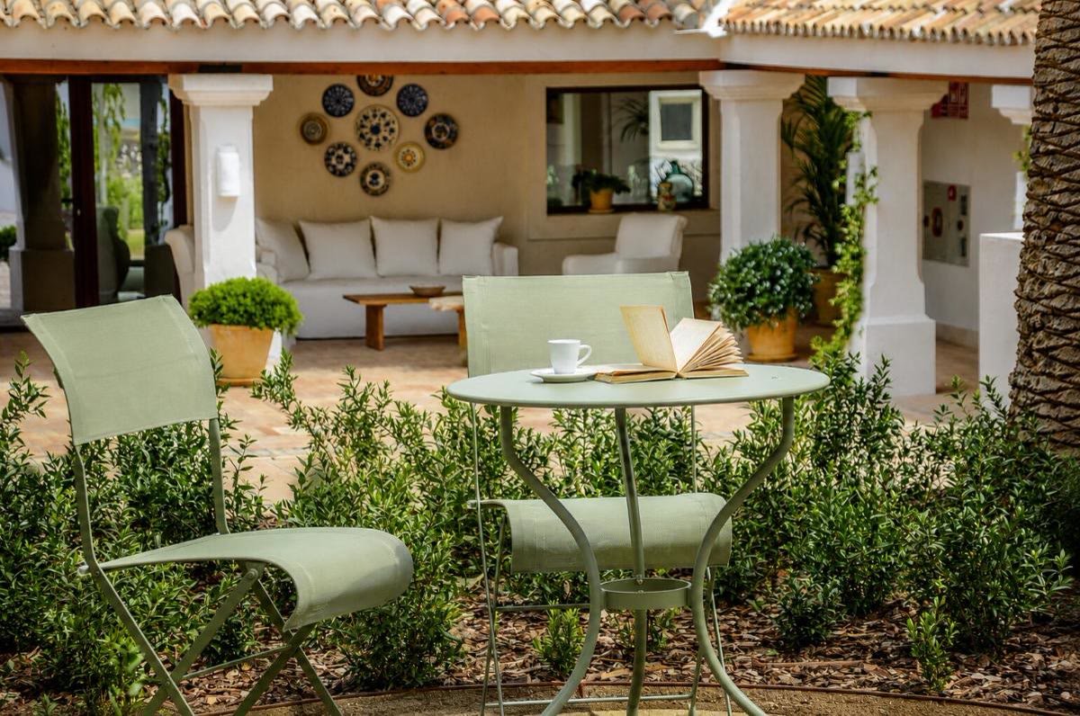 Porche con plantas y mobiliario de exterior en el Monasterio